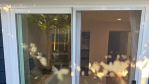 Een glazen schuindeur die leidt naar een kamer met een bed, een klein tafeltje en een stoel.