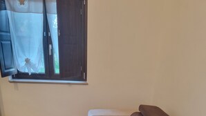 Un salon avec un canapé d’angle et un petit pouf.