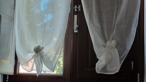 Une porte ornée de deux rideaux, l’un décoré de motifs de papillons et l’autre d’un motif en dentelle.