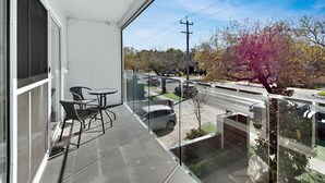 Ein Balkon mit Glasgeländer, einem Tisch und zwei Stühlen.