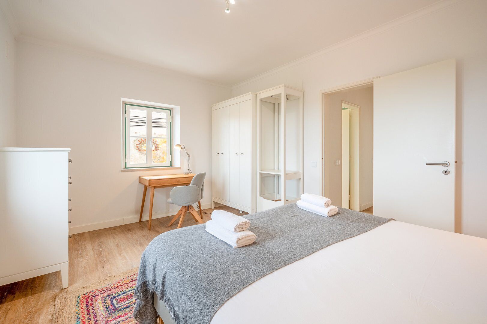 A bedroom with a bed, a desk, and a wardrobe.
