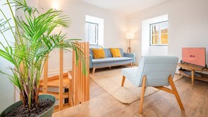Una sala de estar moderna con un sofá, una silla, un televisor y una planta en maceta.