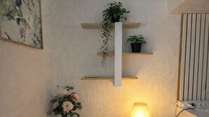 Uma cozinha compacta com uma mesa de madeira, uma cadeira, uma planta pendente e uma prateleira na parede.