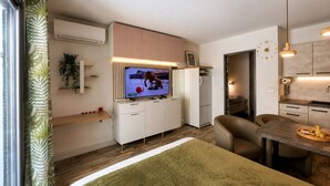 Espaço compacto com televisão, cozinha compacta, área de estar e mesa de jantar.