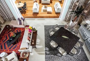 Un salón espacioso con piso de madera, una mesa de comedor con sillas y un conjunto de sofás.