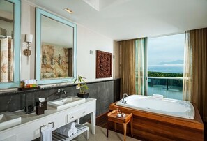 Un baño moderno con un espejo grande, dos lavamanos, una bañera y vistas a la ciudad.