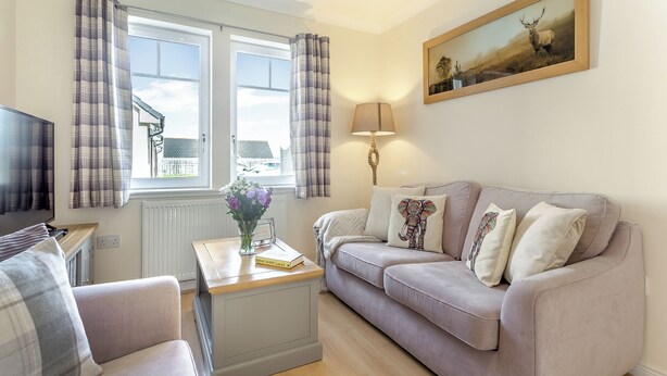 Ein Wohnzimmer mit einer Couch, einem Fernseher, einer Lampe und einem Bild an der Wand.