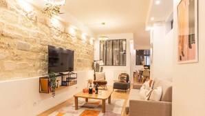 Una sala de estar moderna con pared de piedra, un televisor de pantalla plana, una mesa de centro y un sofá.