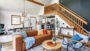 A spacious living area with a brown sofa, a round wooden coffee table, and a staircase with wooden railings. - Blue Diamond Hot Tub Fire Pit 3 BDR (Tobyhanna)