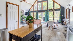 A spacious kitchen with a wooden countertop, a dining area with a table and chairs, and large windows with curtains. - Blue Diamond Hot Tub Fire Pit 3 BDR (Tobyhanna)