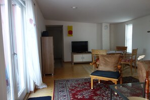 A living room with a television, wooden furniture, a red patterned rug, and a wooden cabinet. - Holiday Home 'Waren An Der Müritz' with Lake View, Private Terrace and Wi-Fi (Waren (Müritz))