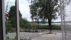 A wooden deck with a stone pathway leading to a fenced area with a view of a lake and trees. - Holiday Home 'Waren An Der Müritz' with Lake View, Private Terrace and Wi-Fi (Waren (Müritz))