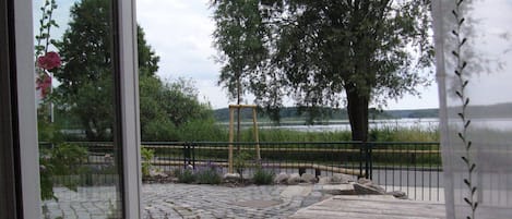 A wooden deck with a stone pathway leading to a fenced area with a view of a lake and trees.