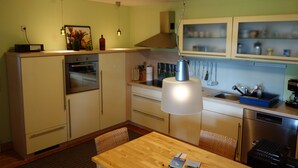 A compact kitchen with a wooden table, built-in cabinets, a stove, and a dishwasher. - Holiday Home 'Waren An Der Müritz' with Lake View, Private Terrace and Wi-Fi (Waren (Müritz))