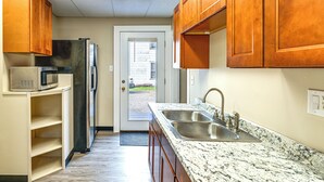 A kitchen with wooden cabinets, a stainless steel sink, and a microwave. - Walk to Dtwn Seneca Falls: Family Retreat w/ Yard! (Seneca Falls)