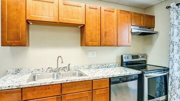 A kitchen with wooden cabinets, a stainless steel sink, a dishwasher, and an oven.