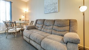 A cozy living room with a grey sofa, a dining table with chairs, and a floor lamp. - Walk to Dtwn Seneca Falls: Family Retreat w/ Yard! (Seneca Falls)
