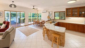 A modern kitchen with a central island, wooden cabinets, and a dining area with chairs.