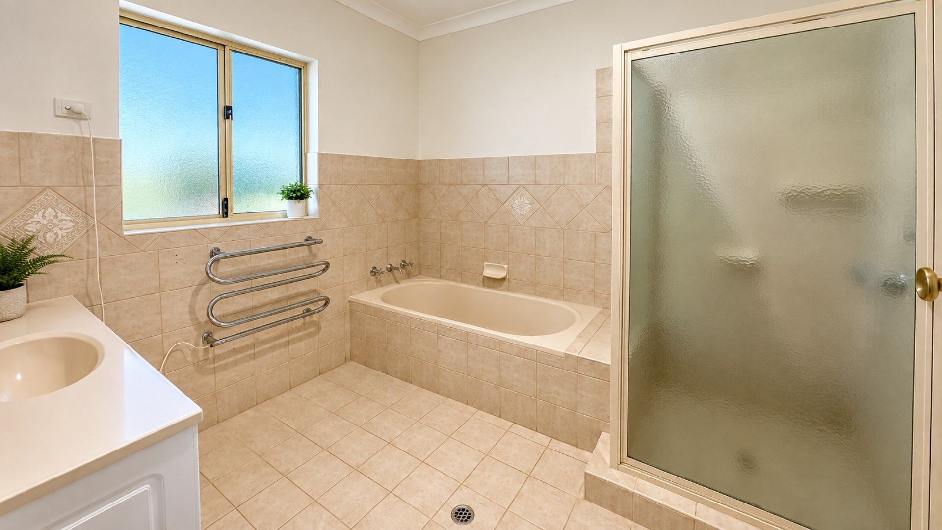 A bathroom with a bathtub, a shower area with glass doors, a window, and a towel rack.