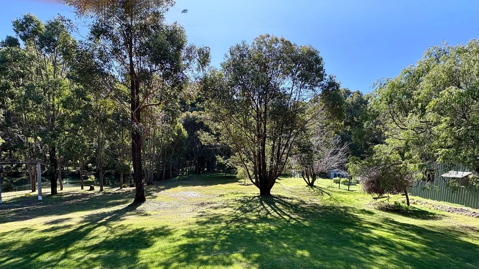 A park with multiple trees, a grassy area, and a fence.