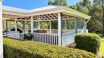 A covered outdoor area with a patio, seating, and a grill.