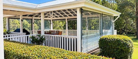 A covered outdoor area with a patio, seating, and a grill.