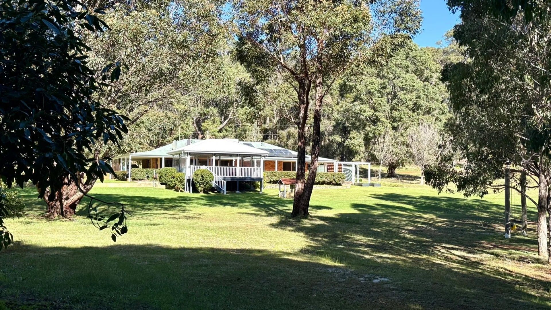 A house with a covered porch, surrounded by trees and grass.