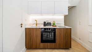 Una cocina compacta con horno integrado, cafetera y un pequeño objeto decorativo en la encimera.