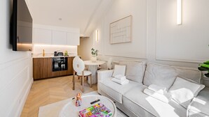 Una sala moderna con un sofá, una mesa de centro y una pequeña mesa de comedor. Hay una zona de cocina con estufa y armarios.