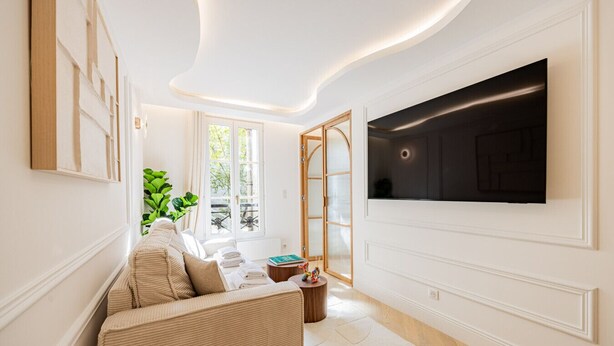 A modern living room with a sofa, a coffee table, and a TV mounted on the wall.