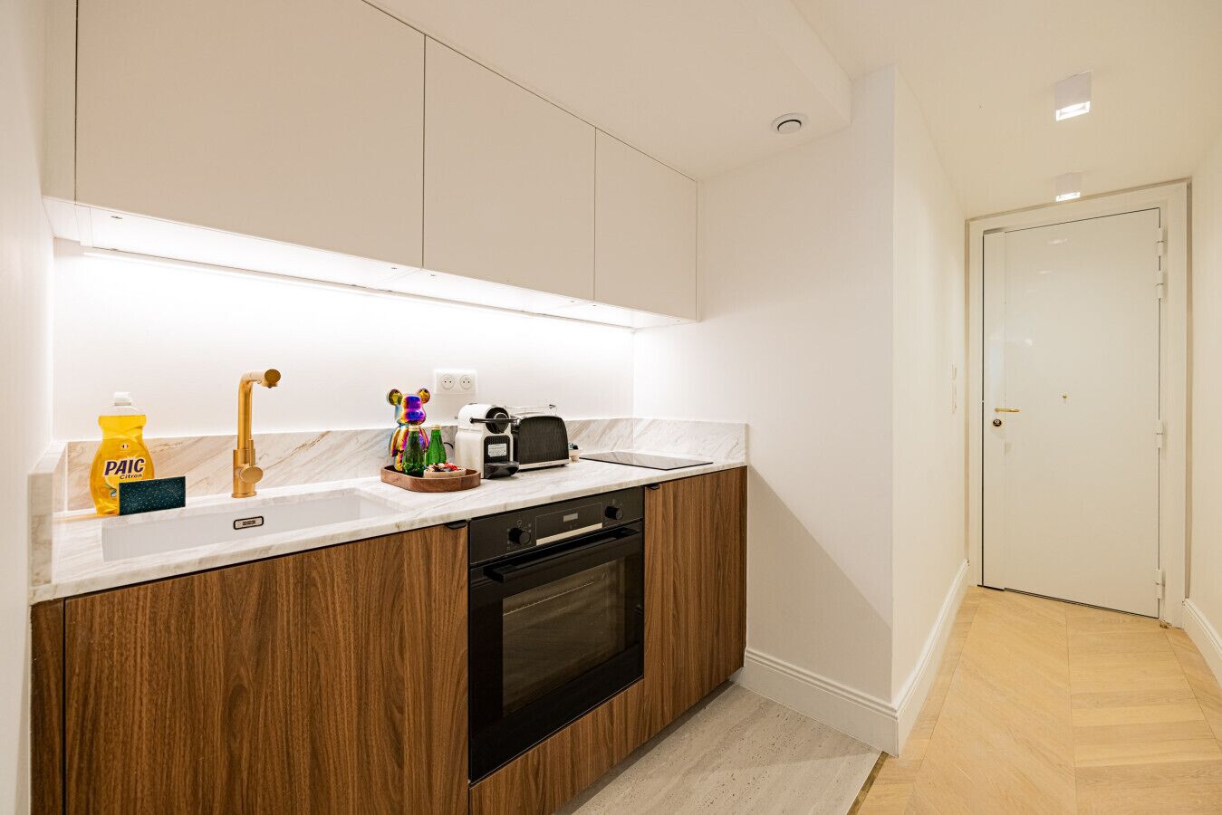 Una cocina moderna con armarios blancos, encimera de madera, horno empotrado y un lavabo con grifo.