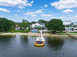 Un río con un muelle flotante y una casa al fondo.