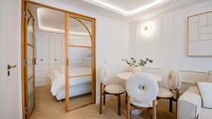 A modern room with a wooden-framed sliding door, a round table with chairs, a sofa, and a small potted plant.