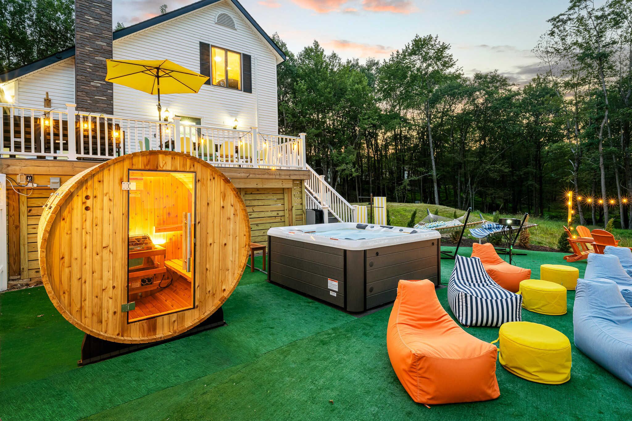Une structure de sauna en bois, un bain à remous et un espace extérieur avec des sièges et des coussins.
