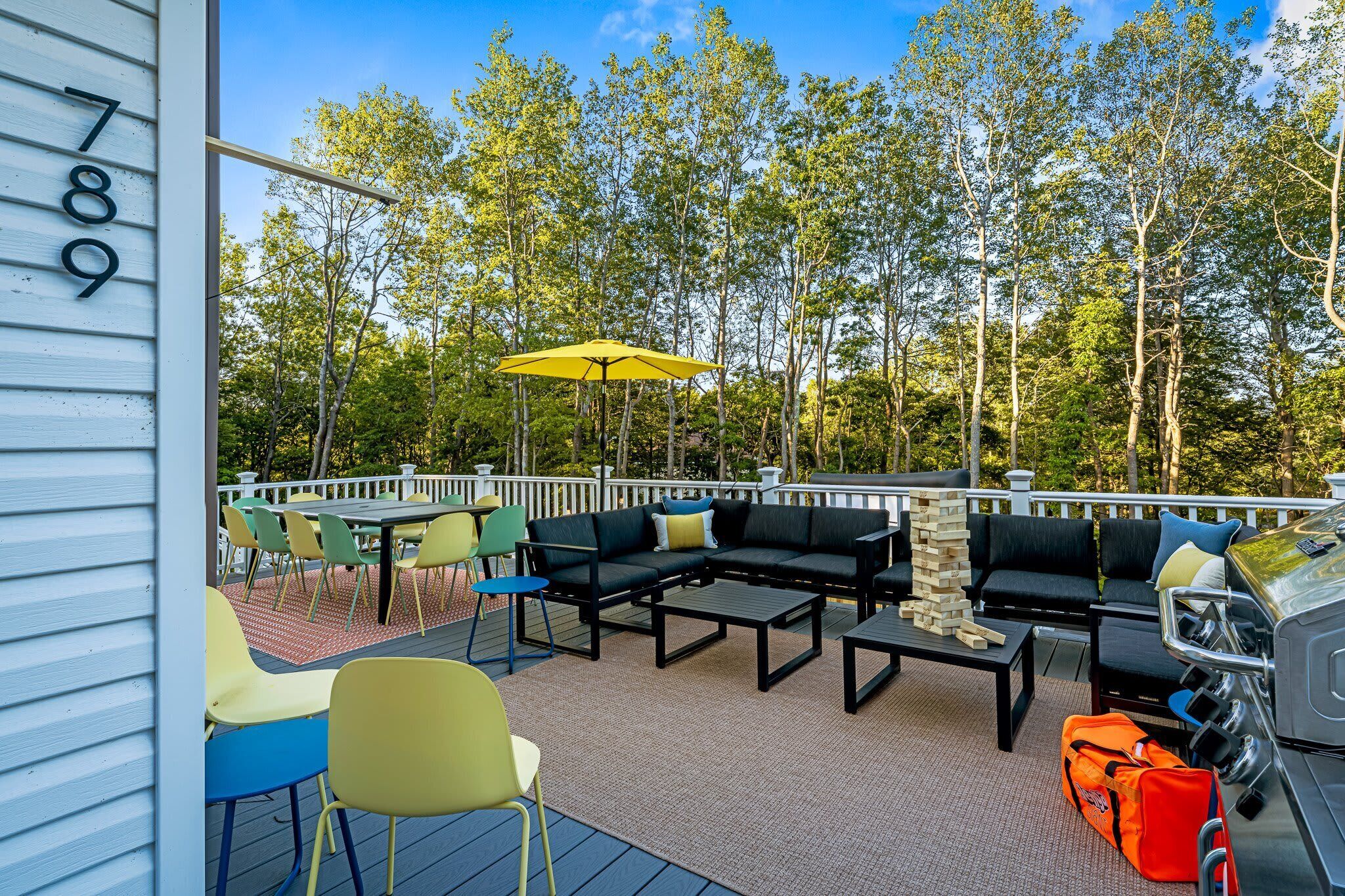 Eine Terrasse mit Gartenmöbeln, einem Grill und Blick auf Bäume.