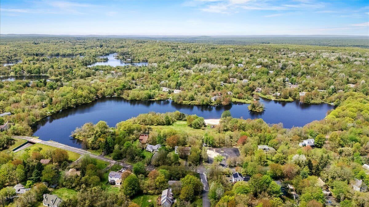 Vista aérea de una zona residencial con un lago grande rodeado de casas y vegetación.