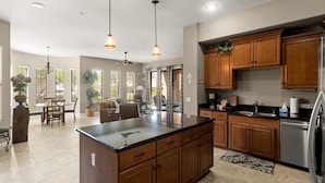 A spacious kitchen with wooden cabinets, a large island, and pendant lighting. - Shared Poolside Fun~Hot Tub~Gym & More (Phoenix)
