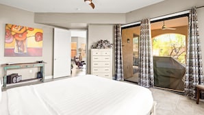 A bedroom with a bed, a ceiling fan, a painting, a dresser, a desk, and a sliding glass door leading to an outdoor area. - Shared Poolside Fun~Hot Tub~Gym & More (Phoenix)