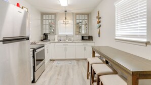 Eine moderne Küche mit weißen Schränken, einem eingebauten Backofen, einer Mikrowelle und einem Holzespeisetisch mit Bänken.
