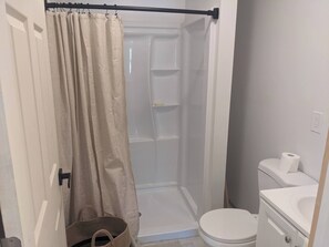 Un baño pequeño con ducha, inodoro y lavamanos.