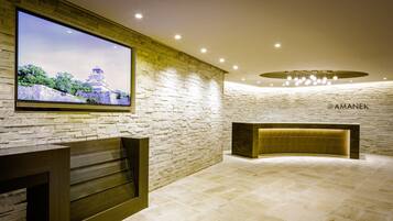 A reception area with a stone wall, a television displaying a scenic view, and a reception desk.