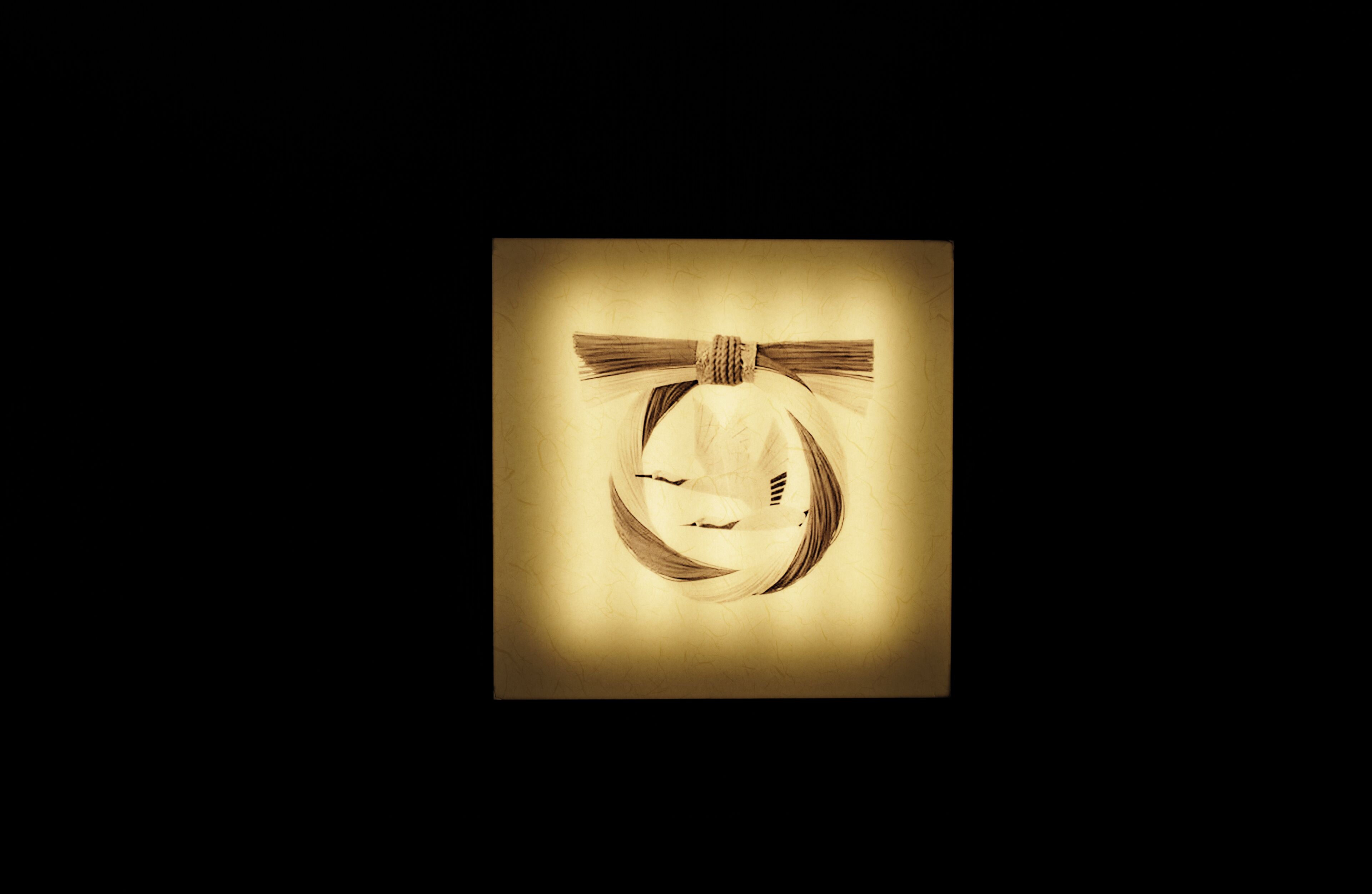 A square frame with a central object that appears to be a pumpkin with a bow, set against a dark background.