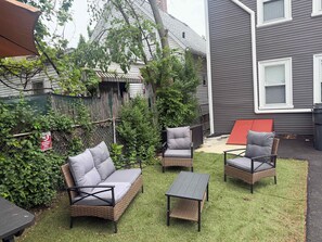 A patio with wicker furniture, a small table, and a red folding table.