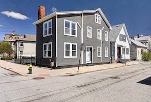 A two-story residential building with a gray exterior, white trim, and multiple windows.