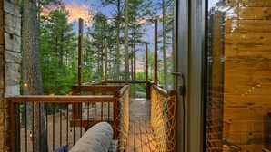 A wooden deck with a rope barrier, stone walls, and a bench. - Sleeps 18 people with a private heated pool, hot tub, playground, fire pit, and a private arcade! (Broken Bow)