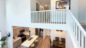 Une cuisine moderne dotée d’un îlot central, d’un coin repas avec une table et des chaises, et d’un escalier menant à un niveau supérieur.