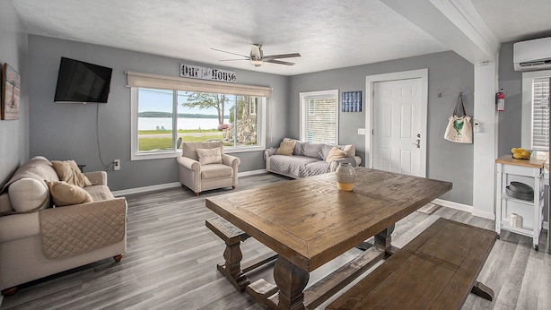 A living room with a wooden table, two sofas, a television, and a ceiling fan.