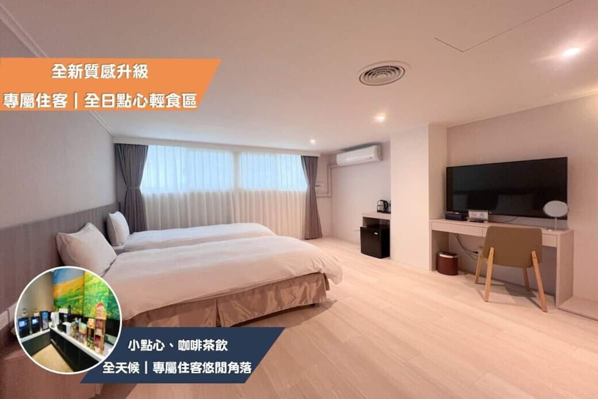 Ein modernes Hotelzimmer mit einem großen Bett, einem Schreibtisch mit Computer und einem Fernseher.
