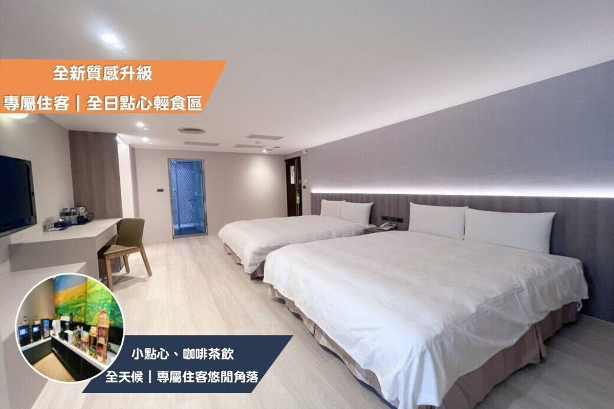 Ein modernes Hotelzimmer mit zwei Betten, einem Schreibtisch und einer Sitzecke.