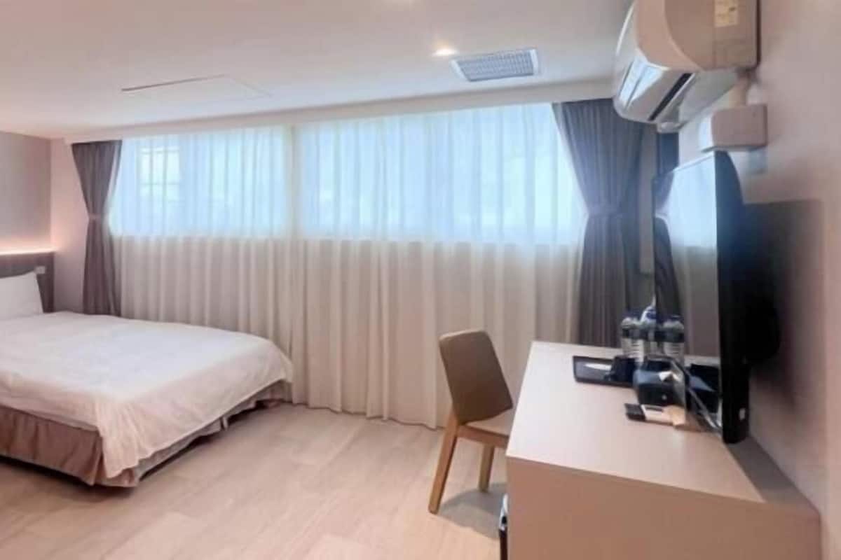 Ein modernes Hotelzimmer mit zwei Betten, einem Schreibtisch und einem Fernseher.